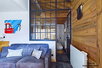 A living room with a couch and a white management sign on the wall