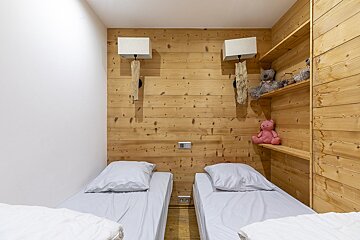 A bedroom with two beds and a pink teddy bear on a shelf