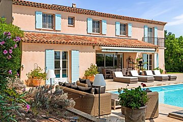 Sunny Mediterranean villa with peach walls, blue shutters, a tiled roof, outdoor lounge, and a sparkling pool.
