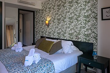 A hotel room with a bed and slippers on the bed