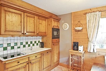 A kitchen with wooden cabinets and a clock on the wall