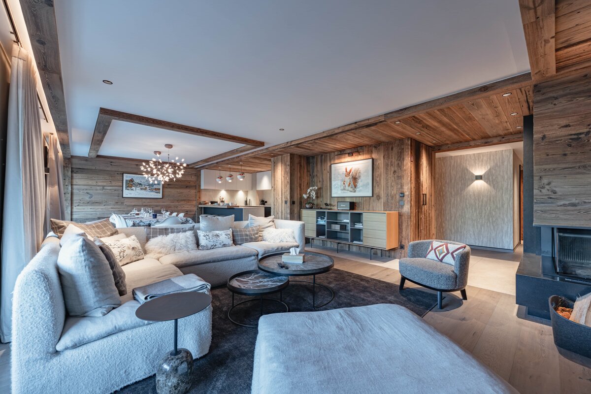 A luxurious modern chalet living room featuring warm wood paneling, a large plush sectional sofa, and stylish contemporary decor.