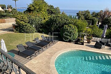 A swimming pool surrounded by chairs and umbrellas with the word home visible in the background
