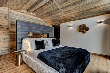 A bed with a blue blanket and black pillows in a bedroom