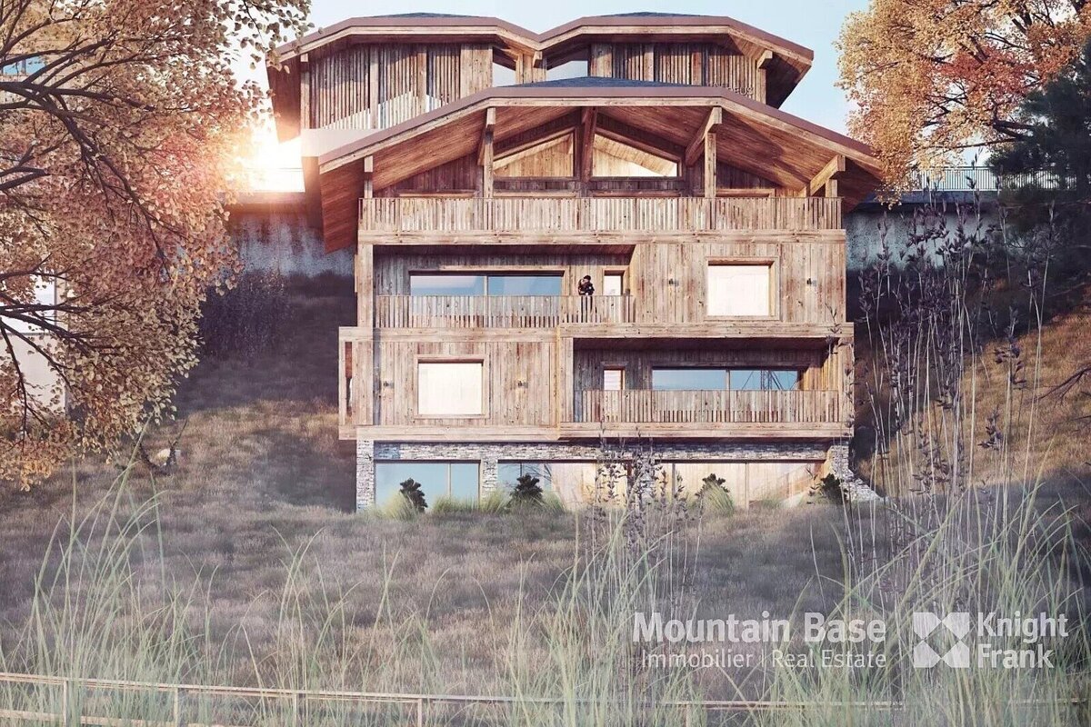 A grand, multi-story wooden chalet with balconies stands on a grassy hillside with autumn trees, bathed in the warm light of sunrise or sunset.