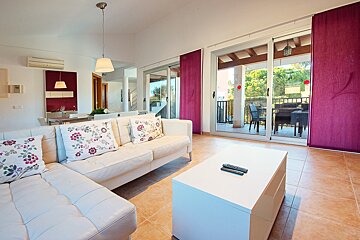 A living room with a white couch and purple curtains