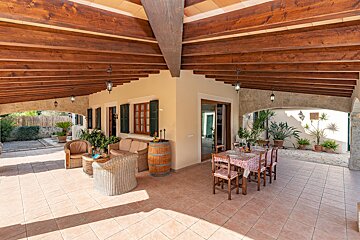 A patio with a table and chairs under a wooden roof