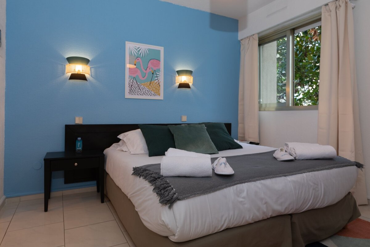 A bedroom with a bed and a picture of a flamingo on the wall