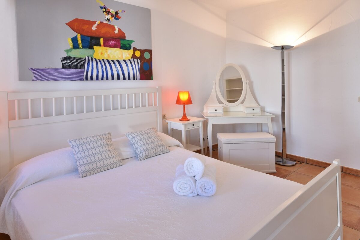 A bedroom with a large painting on the wall above the bed