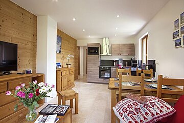 A living room with a table and chairs and a tv