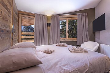 A bedroom with a large bed and a flat screen tv