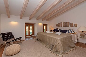 A bedroom with a large bed and a chair
