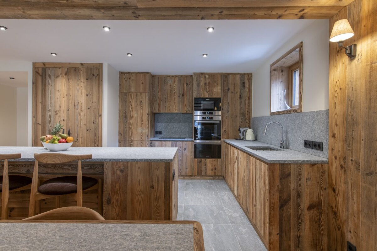 A kitchen with wooden cabinets and a bowl of fruit on the counter