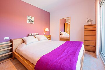 A bedroom with pink walls and a bed with a purple blanket