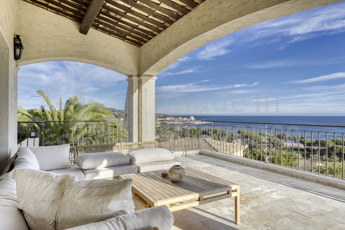 A balcony with a view of the ocean and a couch and table