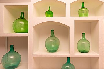 Several green bottles are on a white shelf