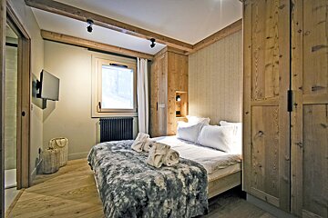A bedroom with a bed and a television on the wall