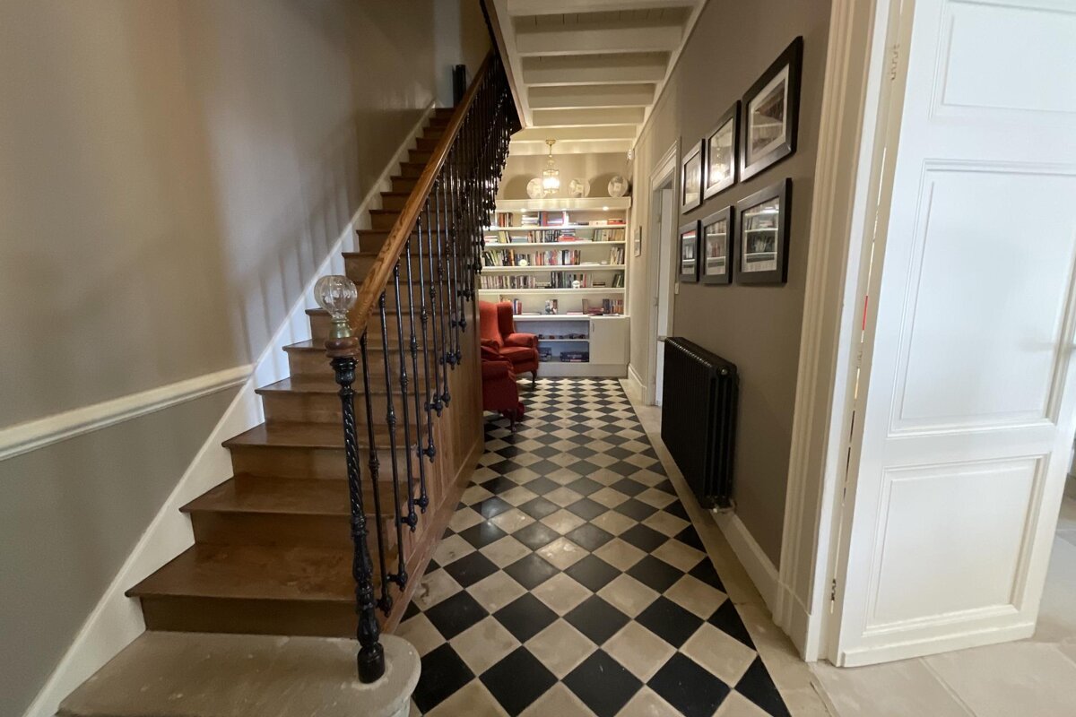 A hallway with stairs and a black and white checkered floor