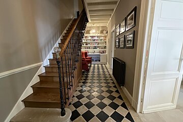 A hallway with stairs and a black and white checkered floor