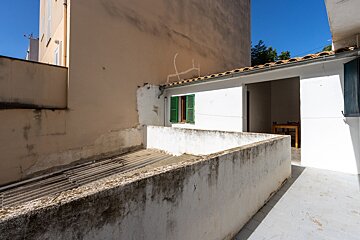 A white wall with a window with green shutters