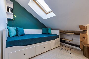 A bed with blue pillows and a skylight above it