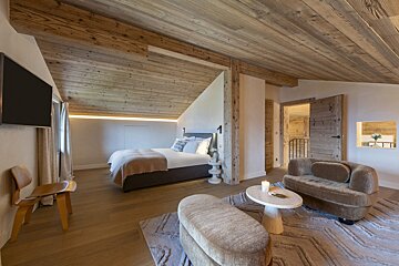 A bedroom with a wooden ceiling and a large bed