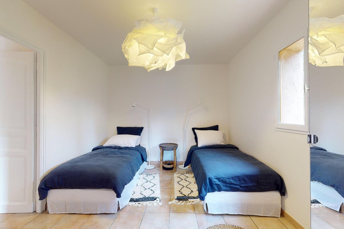 A bedroom with two beds and a mirror