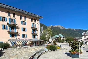 A sunny town square features a pink