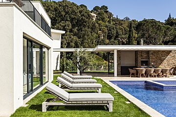 A row of lounge chairs sit next to a swimming pool