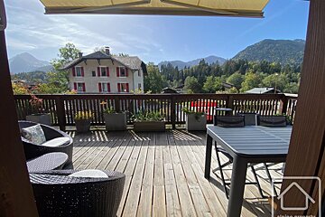 A balcony with a table and chairs and mountains in the background