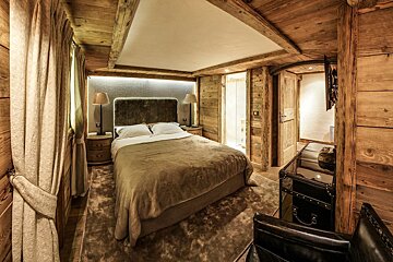 A bedroom with a bed and a trunk in the corner
