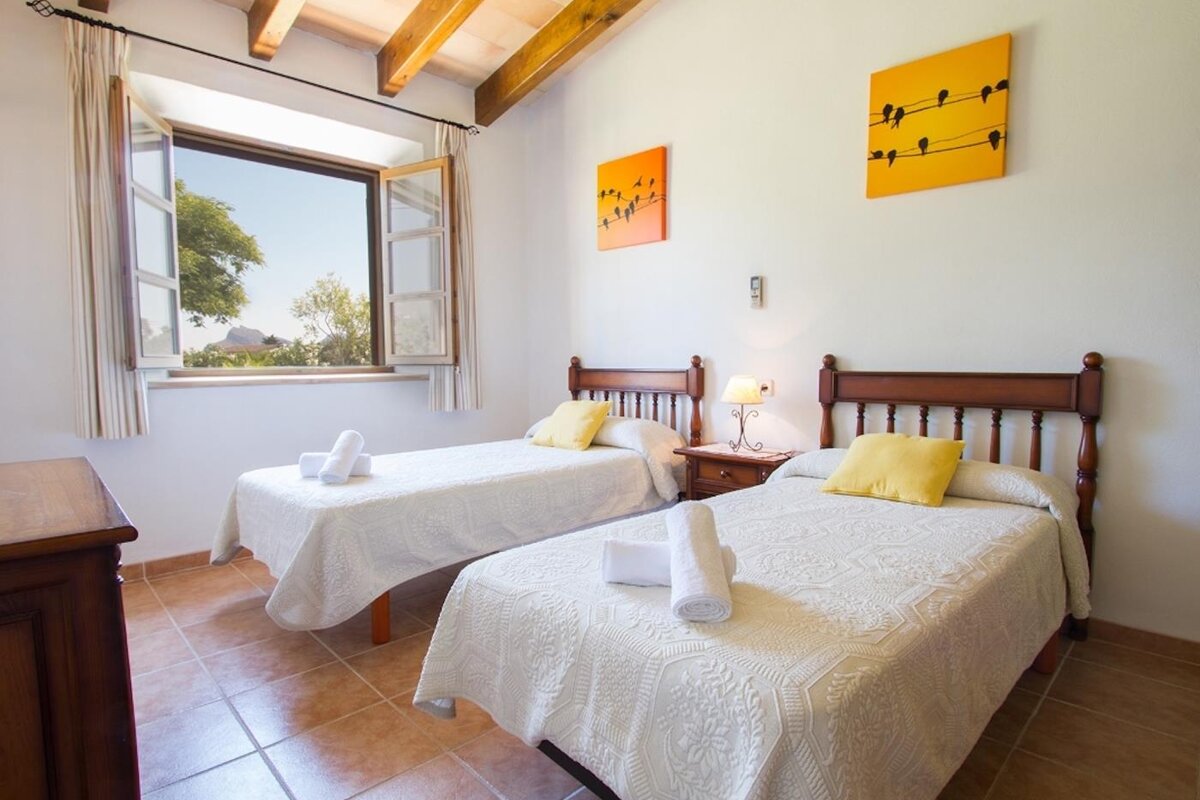 A bedroom with two twin beds and two paintings on the wall