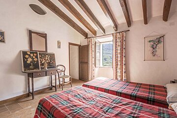 A bedroom with two beds and a painting on the wall