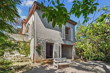 A white bench sits in front of a house with white shutters