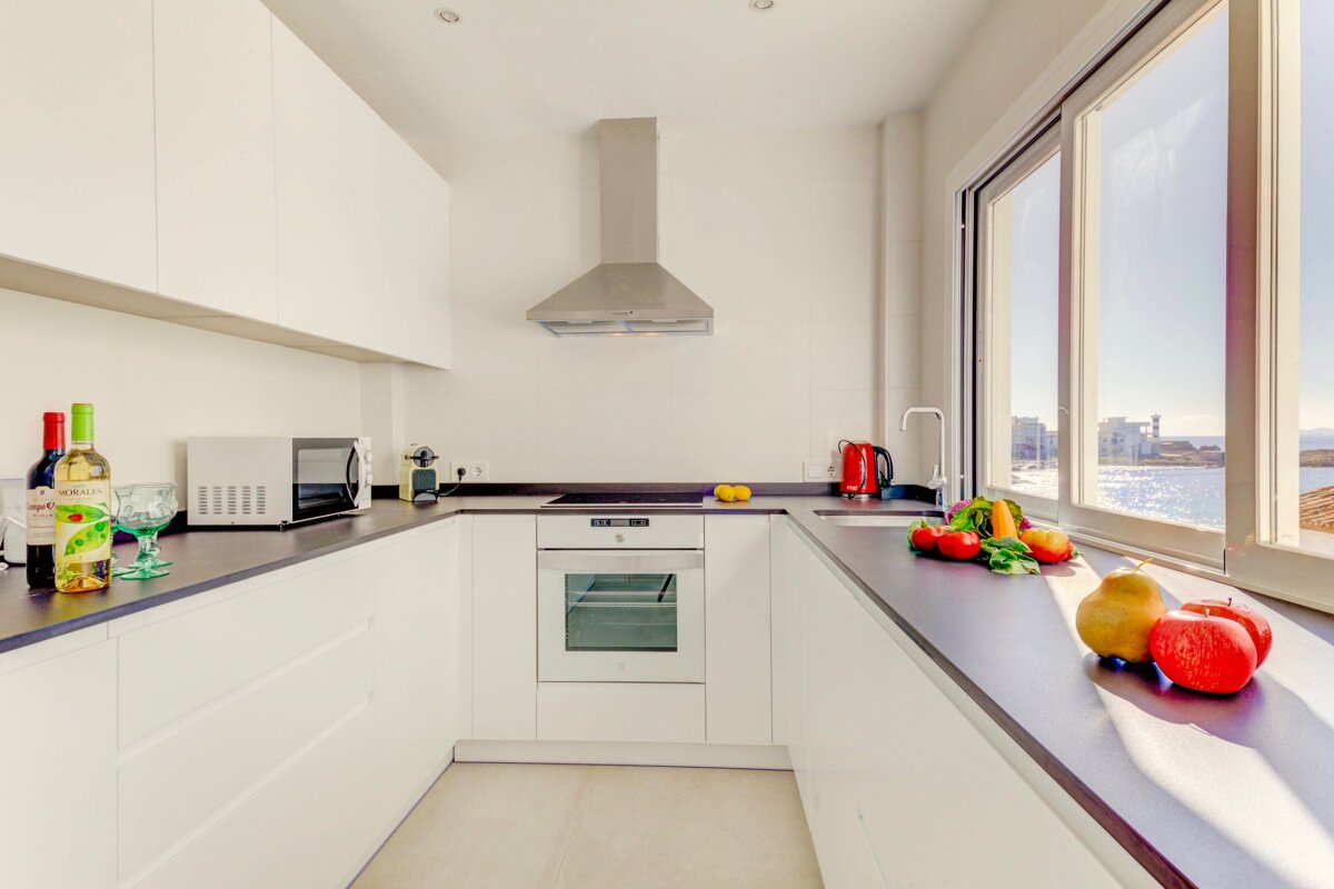 A kitchen with fruits and vegetables on the counter and a bottle of wine that says ' rioja ' on it