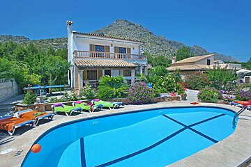 A swimming pool in front of a house with a mountain in the background