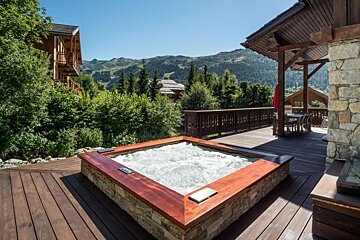 A hot tub on a deck with mountains in the background