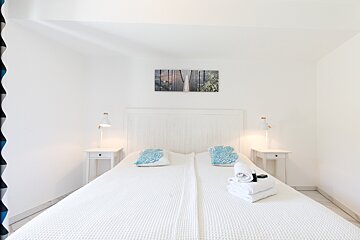 A bedroom with a white bed and two nightstands