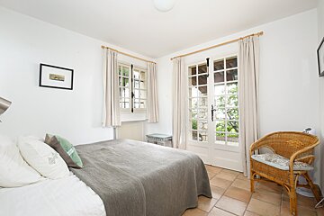 A bedroom with a wicker chair and a bed