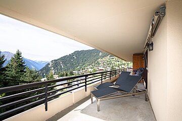 A balcony with two lounge chairs and a view of the mountains