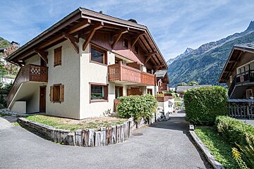 A house with a balcony and mountains in the background