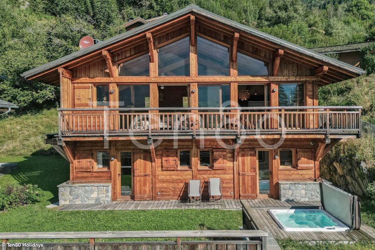 A large wooden house with a hot tub in front of it