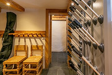 A wooden chair sits next to a row of skis