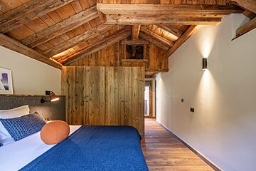A bedroom with a wooden ceiling and a bed