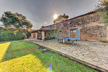 A stone patio with a ping pong table in front of a house