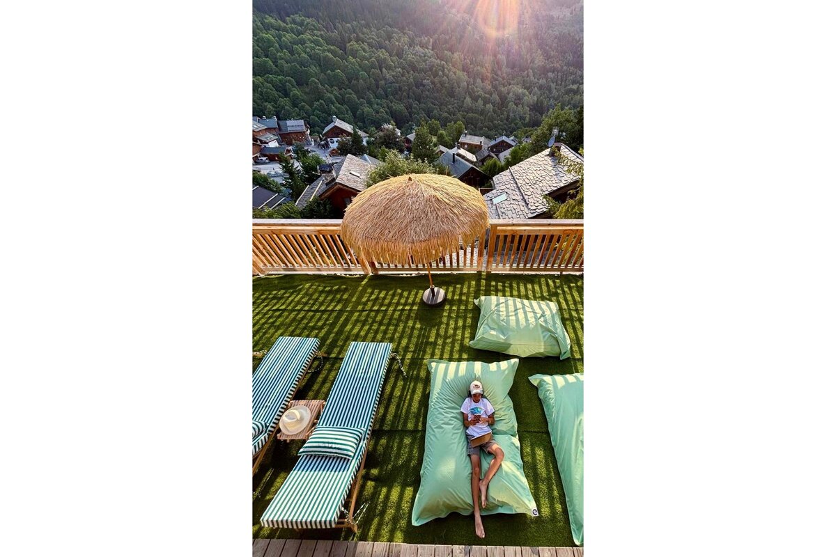 A woman is laying on a bean bag chair on a patio