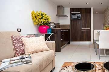 A living room with a couch a magazine and a vase of flowers