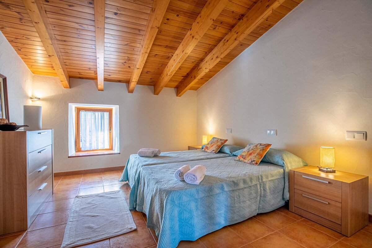 A bedroom with two beds and a wooden ceiling