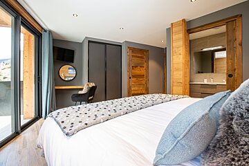 A bedroom with a large bed and a mirror