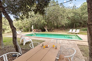 A large swimming pool with a table and chairs in front of it